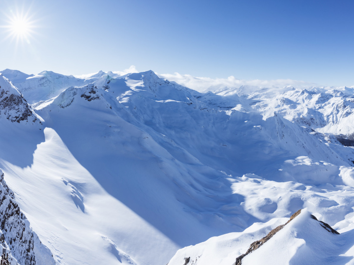 © SalzburgerLand Tourismus Verschneite Berglandschaft mit sonnigem Panoramablick auf die Gipfel der Alpen.