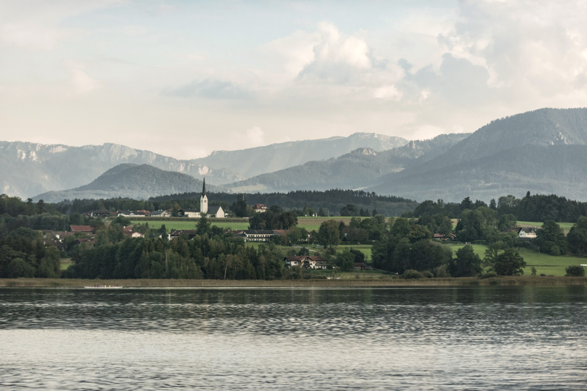 © Bayern Tourismus Marketing GmbH Wooded hill landscape with a church in Upper Bavaria. A river flows through the foreground.