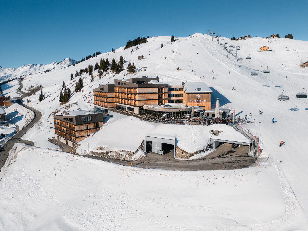 Hotel Alpenstern liegt direkt an der Skipiste in verschneiter Alpenlandschaft, umgeben von Skiliften und Bergen.