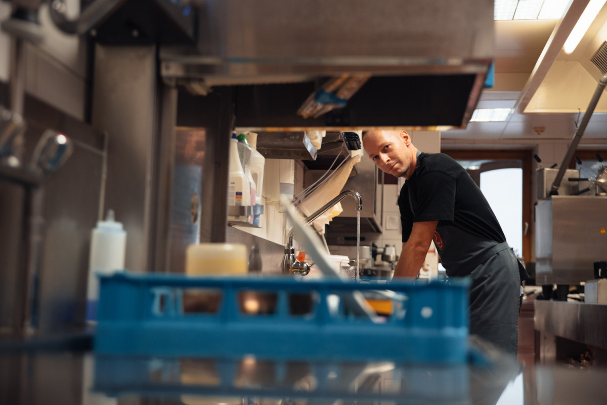Küchenmitarbeiter arbeitet an einer Spüle in der Großküche.