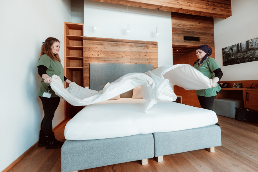 Zwei Zimmermädchen richten ein Bett in einem Hotelzimmer her.