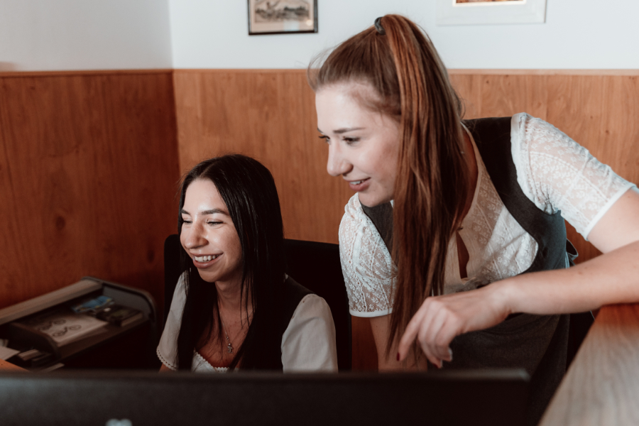 Two women are working on a computer.