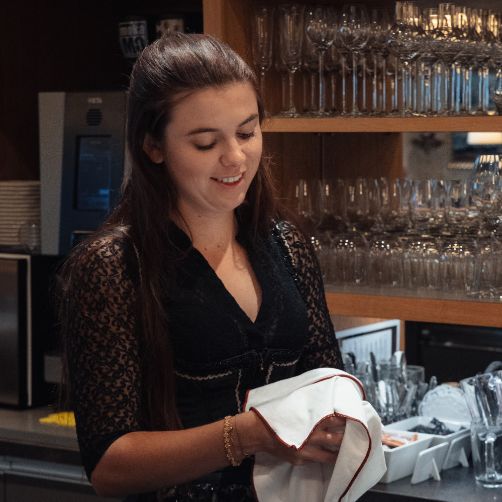 Servicemitarbeiterin poliert ein Weinglas im Restaurant