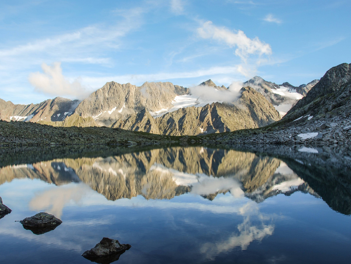 © Tirol Werbung, Jannis Braun Hochalpiner Bergsee mit Spiegelung der umliegenden Felsgipfel im ruhigen Wasser.