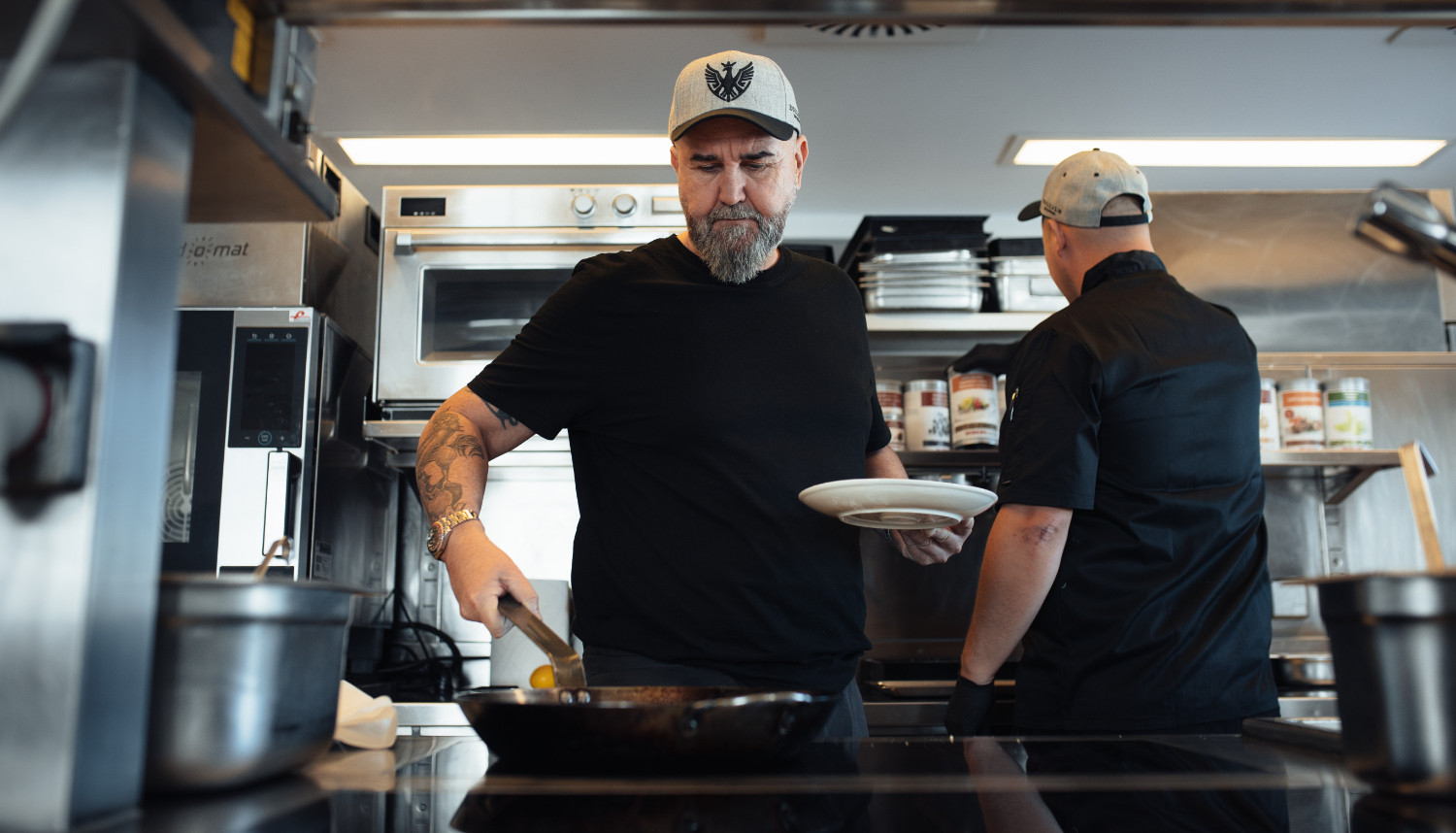 A chef places a piece of meat on a plate.