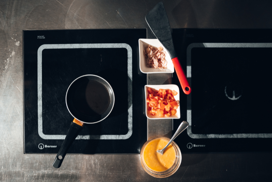 Foto von einer Kochplatte mit Pfanne und Zutaten von oben.