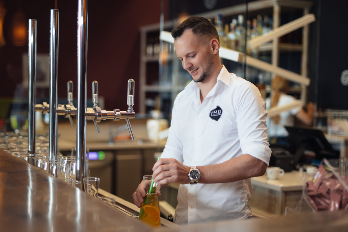 Barkeeper, der am Tresen ein Getränk mixt.