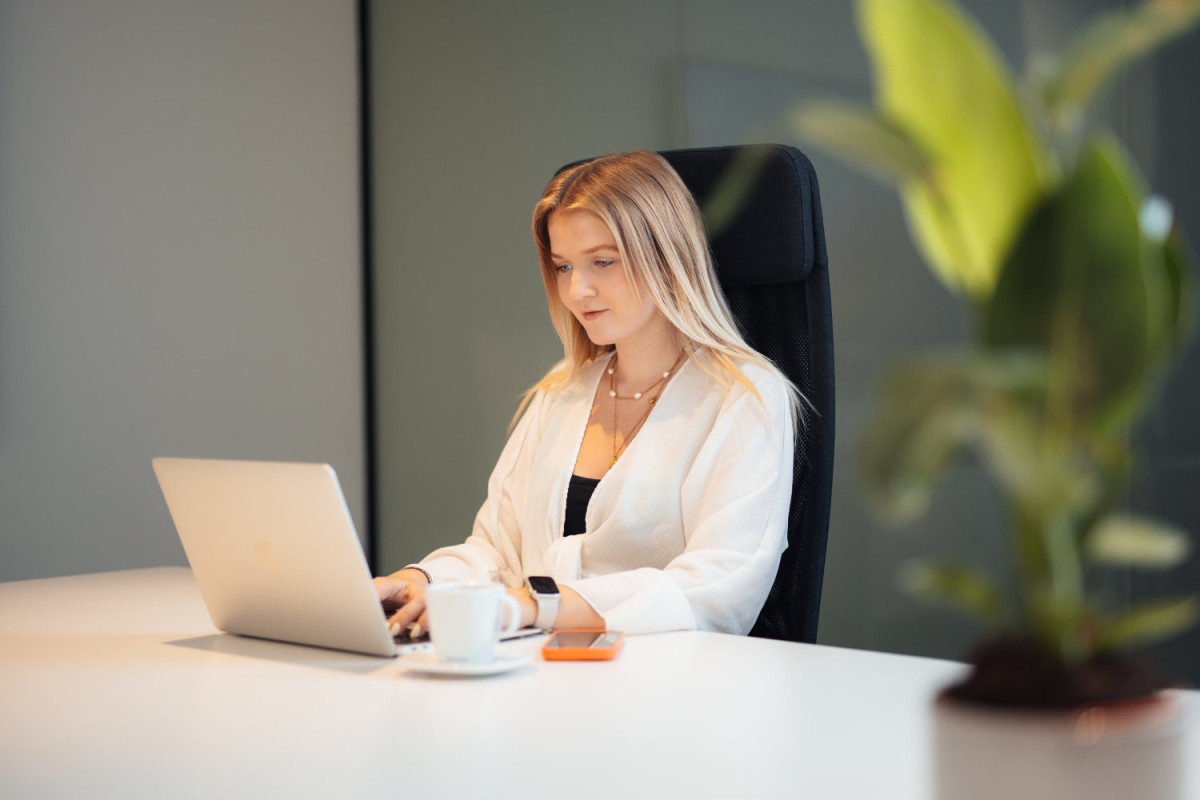 A woman is working on a laptop in an office.