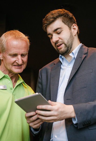 Ein Hotelmanager zeigt einem Mitarbeiter etwas auf einem iPad.