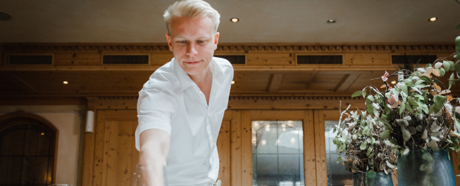 Young waiter in a white shirt setting a table.