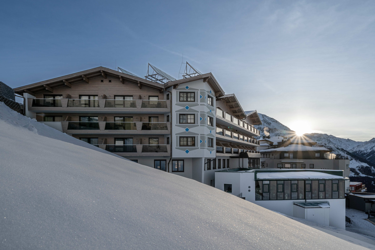 Das Hotel Edelweiss in Tirol im Winter mit Bergkulisse im Hintergrund.