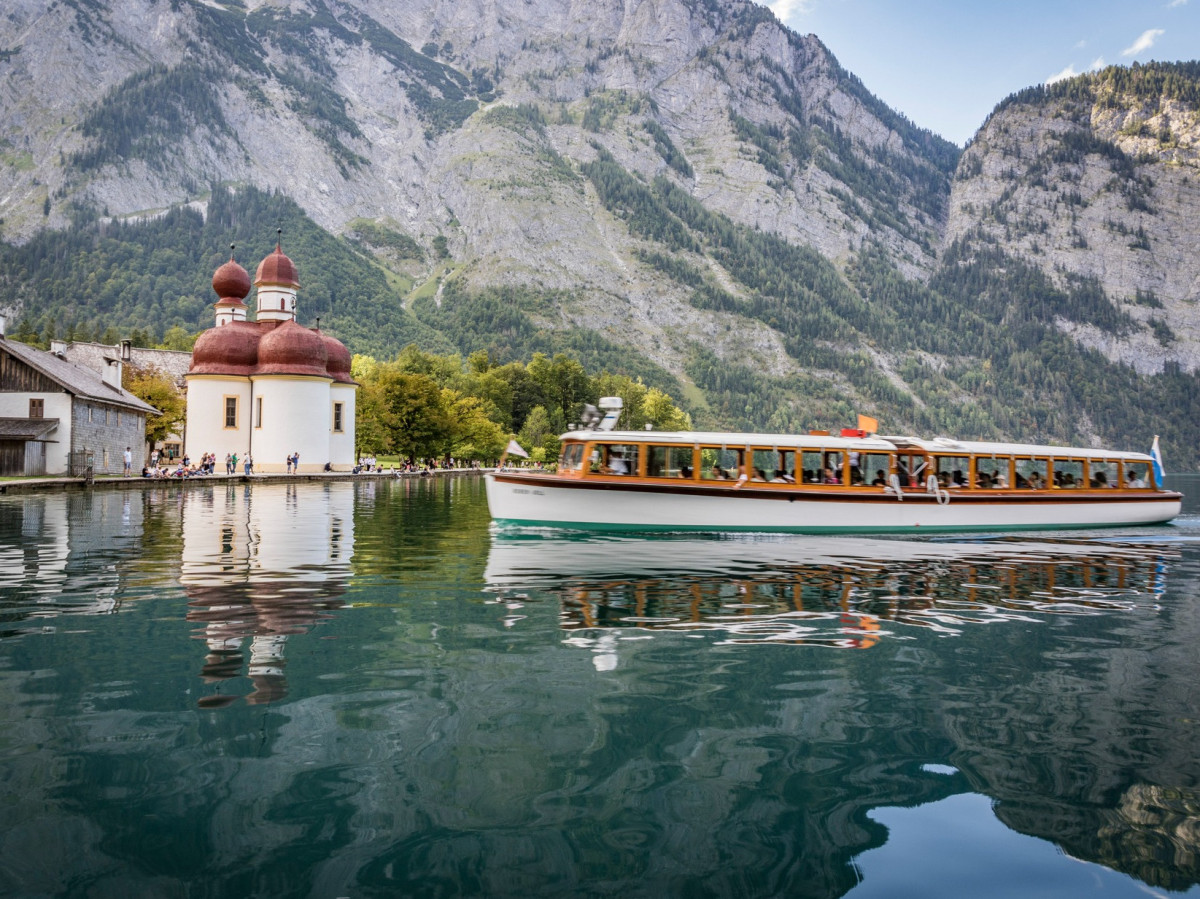 © Bergerlebnis Berchtesgaden Elektroboot, das über den Königssee tuckert. Im Hintergrund das Stift und die Berge.