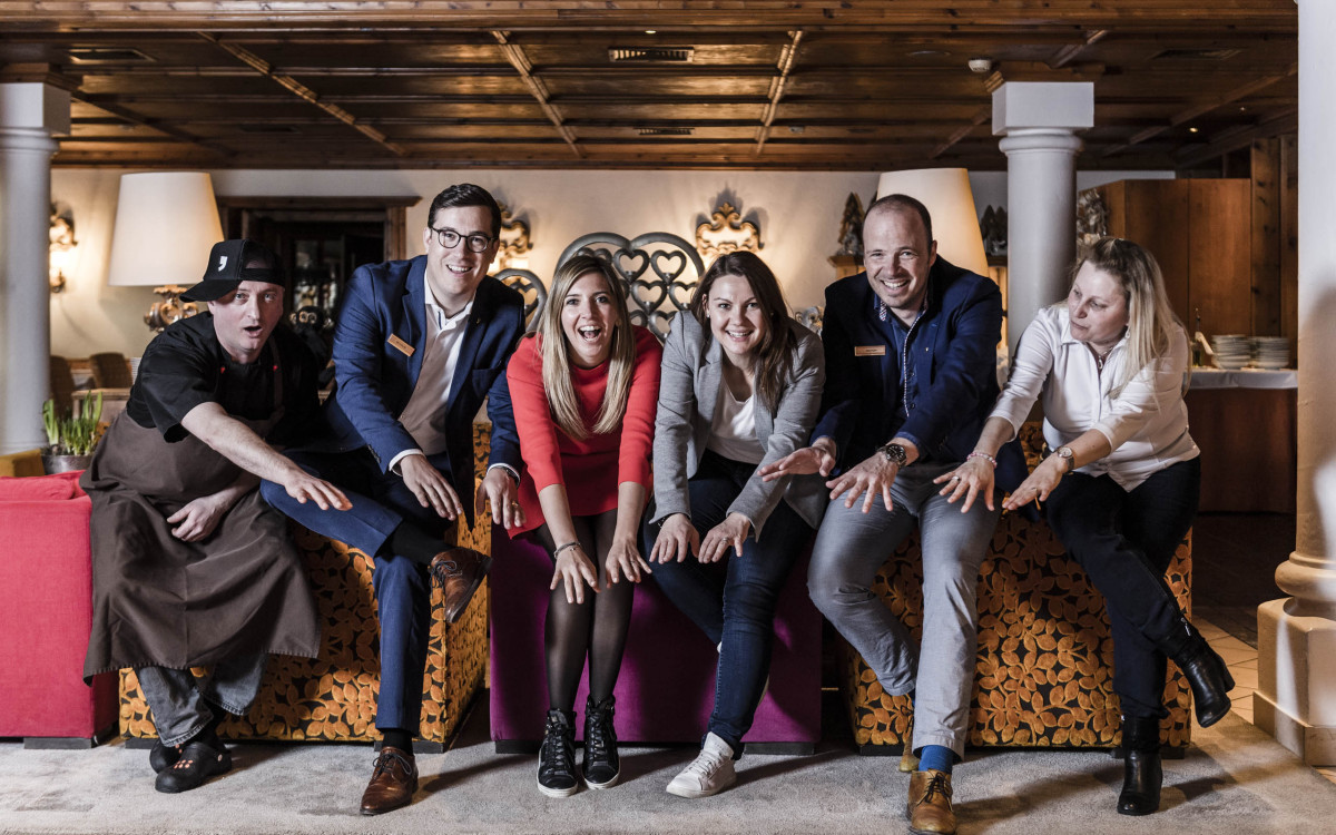 Das Team des Hotels EVA, VILLAGE hält die Hände zusammen und lacht in die Kamera.